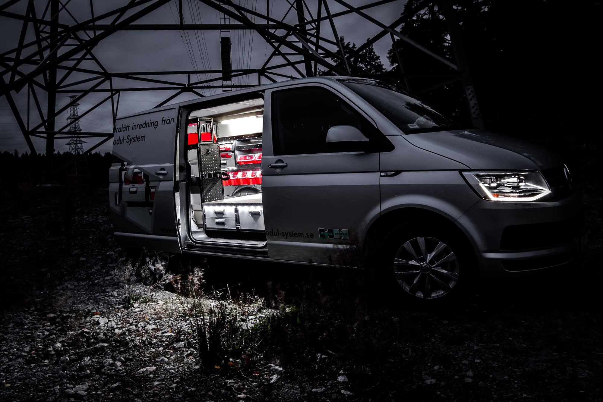 Electrician's van fitted out with modul-system van racking on the job in a field by a pylon