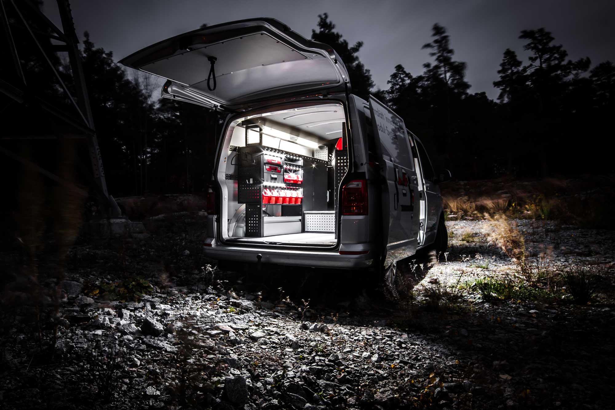 Electrician's van fitted out with modul-system van racking on the job in a field at night